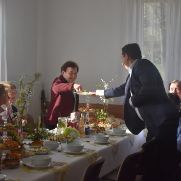 Męzczyzna podający półmisek z jajkami gościom na sali.