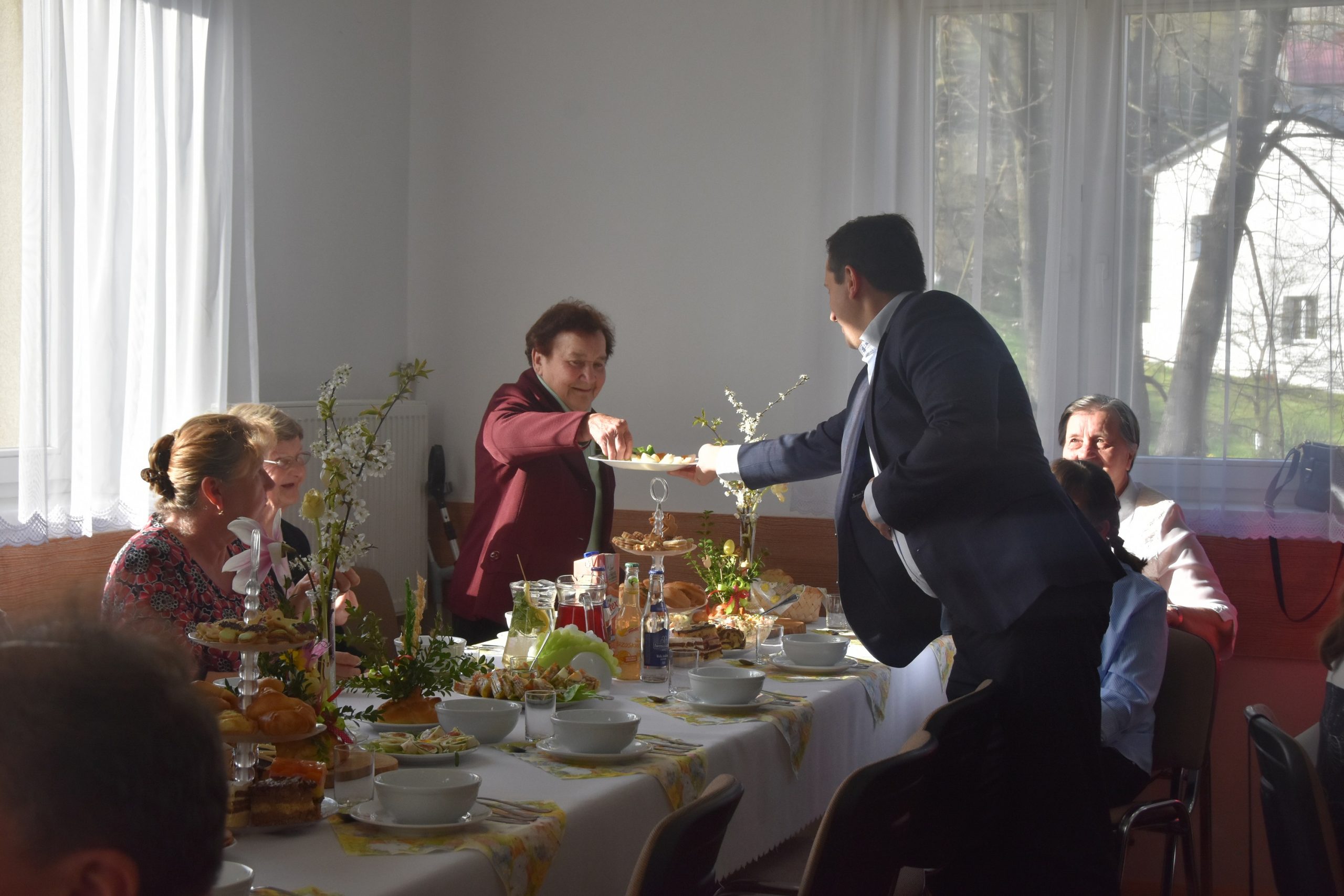 Męzczyzna podający półmisek z jajkami gościom na sali.