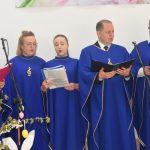 Chór kobiet i męćzyzn w granatowych strojach w czasie występu.