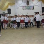 Grupa dzieci w odswiętnych strojach w czasie wystepu na sali.