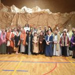 Grupa aktorów i osób zaangażowanych w przedstawienie teatralne "Misterium Męki Pańskiej" na sali gimnastycznej pozująca do wspólnego zdjęcia.