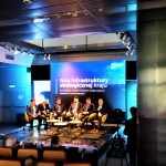 Grupa mężczyzn w garniturach w czasie dabaty na rozległej sali.