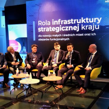 Grupa mężczyzn w garniturach w czasie dabaty na rozległej sali.