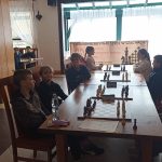 Grupa dzieci grająca w szachy w pomieszczeniu.