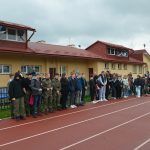 Grupa dorosłych i dzieci stojąca przy stadionie miejskim.