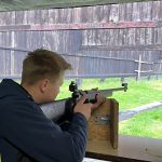 Młody mężczyżna strzelajacy z broni treningowej na strzelnicy.