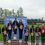 Grupa młodziezy i dorosłych pozujaca do zdjecia na stadionie. Młodzież ma dyplomy i medale.