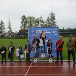 Grupa młodziezy i dorosłych pozujaca do zdjecia na stadionie. Młodzież ma dyplomy i medale.