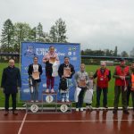 Grupa młodziezy i dorosłych pozujaca do zdjecia na stadionie. Młodzież ma dyplomy i medale.