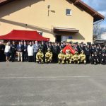 Grupa osób głównie strażaków pozująca do pamiątkowego zdjęcia przed budynkiem straży.