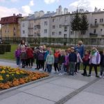 Grupa dzieci przedszkolnych wraz z opiekunami podczas przechadzki po mieście.