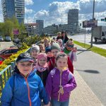 Grupa dzieci przedszkolnych wraz z opiekunami podczas przechadzki po mieście.