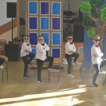 Grupa chłopców w białych koszulach i czarnych spodniach podczas układu tanecznego,