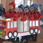 Chłopcy przebrani za strażaków w kartonowym wozie strażackim.