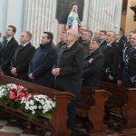 Grupa dorosłych osób (głównie mężczyzn) w płaszczach, garniturach i mundurach w kosciele.