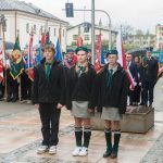 Grupa harcerzy i pocztów sztanadarowych na wolnym powietrzu w mieście.