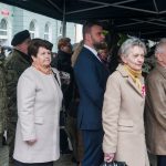 Grupa osób róznej płci wieku stojąca pod namiotem.