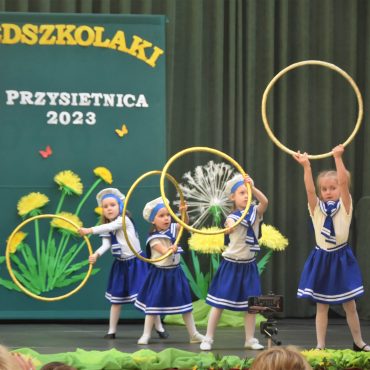 Czwórka dziewczynek w wieku przedszkolnym wykonująca układ taneczny.