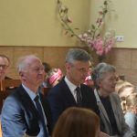 Grupa osób starszych i dzieci obserwujących spektakl.