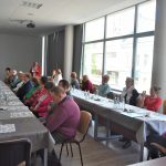 Grupa osób starszych i niepełnosprawnych w sali konferencyjnej urzędu miejskiego