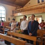 Dwóch mężczyzn i kobieta w eleganckich strojach, w tle grupa ludzi i kobiety w ludowych strojach.