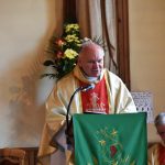 Mężczyzna w szatach stoi przy mównicy i mówi przez mikrofon