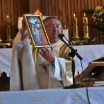 Mężczyzna w szatach trzyma w ręce obraz i mówi przez mikrofon