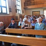 Grupa ludzi siedząca na ławkach w kościele