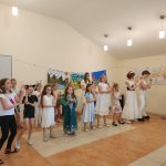 Grupa dzieci tańczy w jasnym pomieszczeniu na dywanie.