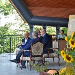 Trzech mężczyzn siedzi na scenie amfitetaru i czyta książkę.