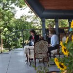 Dwie starsze kobiety siedzą przy stoliku na scenie amfitetaru i czytają książkę. Obok przygotowana piękna sceneria z kwiatów polnych i zbóż.