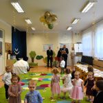 Grupa osób dwie kobiety i dwóch mężczyzn stoją w jasnej sali i przemawiają do dzieci.