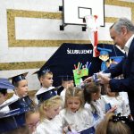 Starszy mężczyzna wręcza upominiki dzieciom.