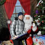 Młody chłopak siedzi na kolanach u swietego mikołaja.