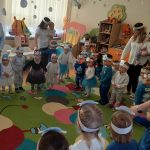 Grupa dzieci bawi się na kolorowym dywanie w przedszkolu.