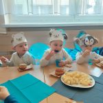 Małe dzieci siedzą przy stoliku i jedzą babeczki.