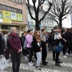 Grupa młodzieży stoi na placu przed urzędem w centrum miasta.