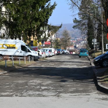 Droga wyboista w centrum miasta, dziurawa z koleinami.