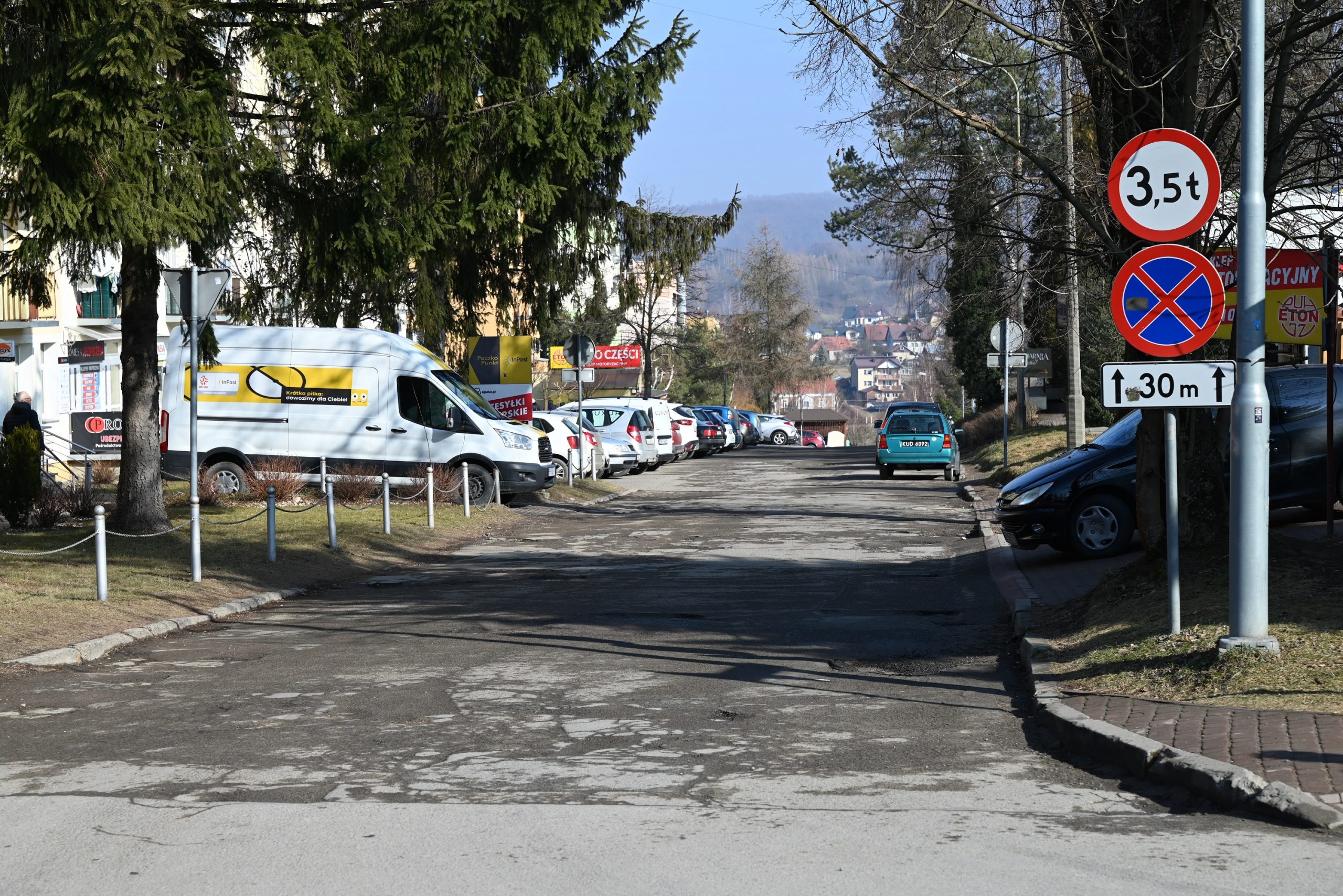 Droga wyboista w centrum miasta, dziurawa z koleinami.