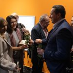 Młody mężczyzna w garniturze wręcza kilku kobietom róże.