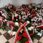 Wiązanki kwiatów biało-czerwone leżą na posadzce.